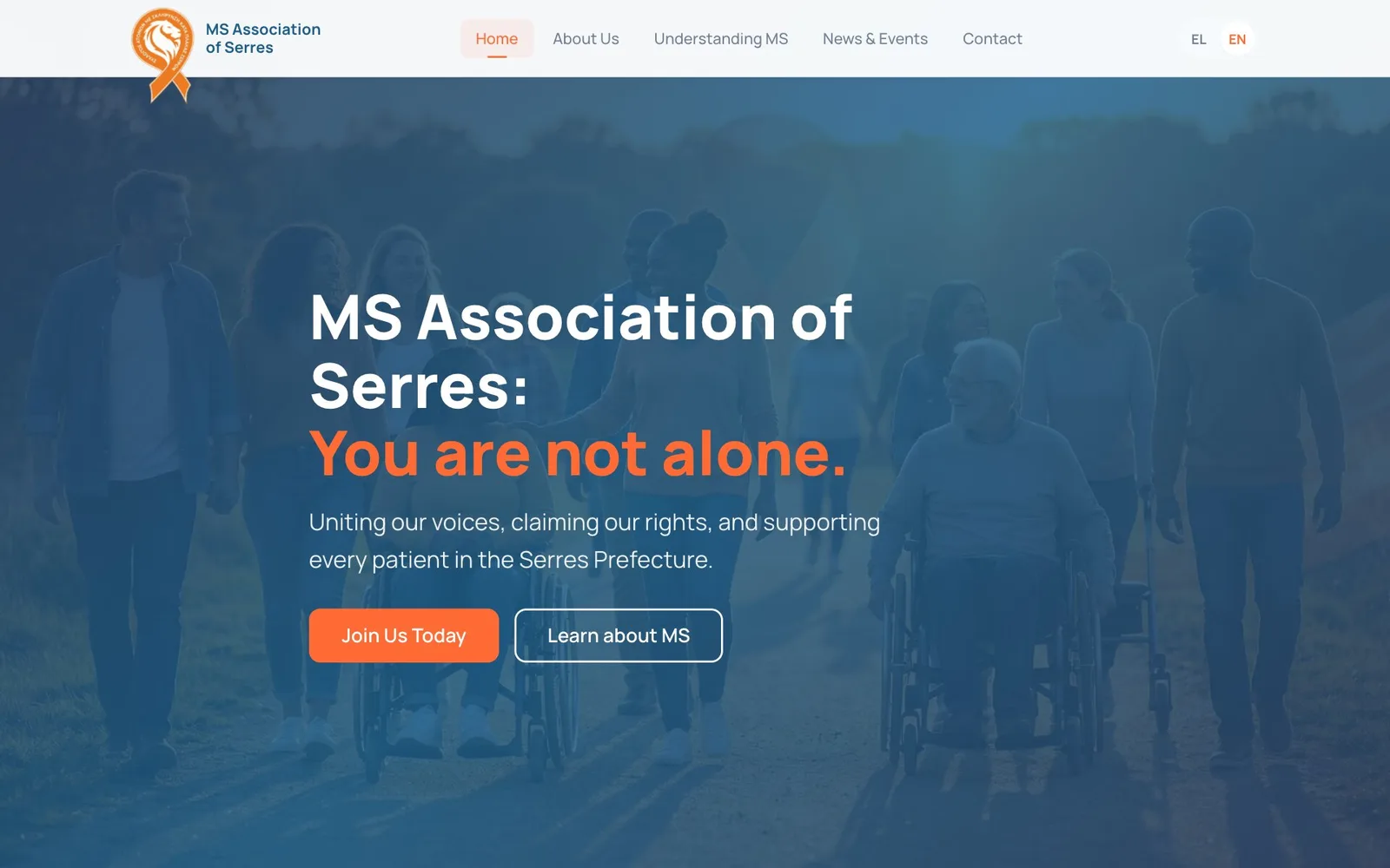 The MS Association of Serres home page in English: the logo, an orange ribbon with a lion's head, and the menu Home, About Us, Understanding MS, News & Events and Contact, with Home highlighted and EN selected; over a blue-tinted photograph of a group of people walking along a path outdoors, some of them in wheelchairs, the headline "MS Association of Serres: You are not alone.", its second line in orange, the line "Uniting our voices, claiming our rights, and supporting every patient in the Serres Prefecture." and an orange "Join Us Today" button beside an outlined "Learn about MS" button.